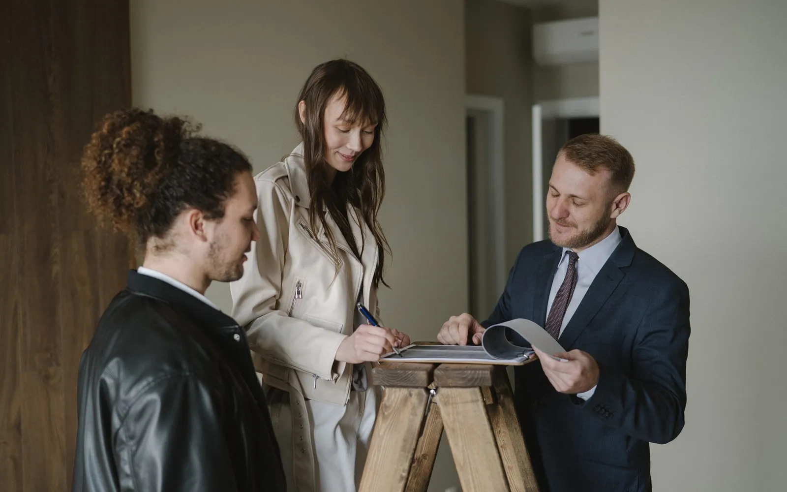 A couple signing paperwork with their real estate agent in a new apartment