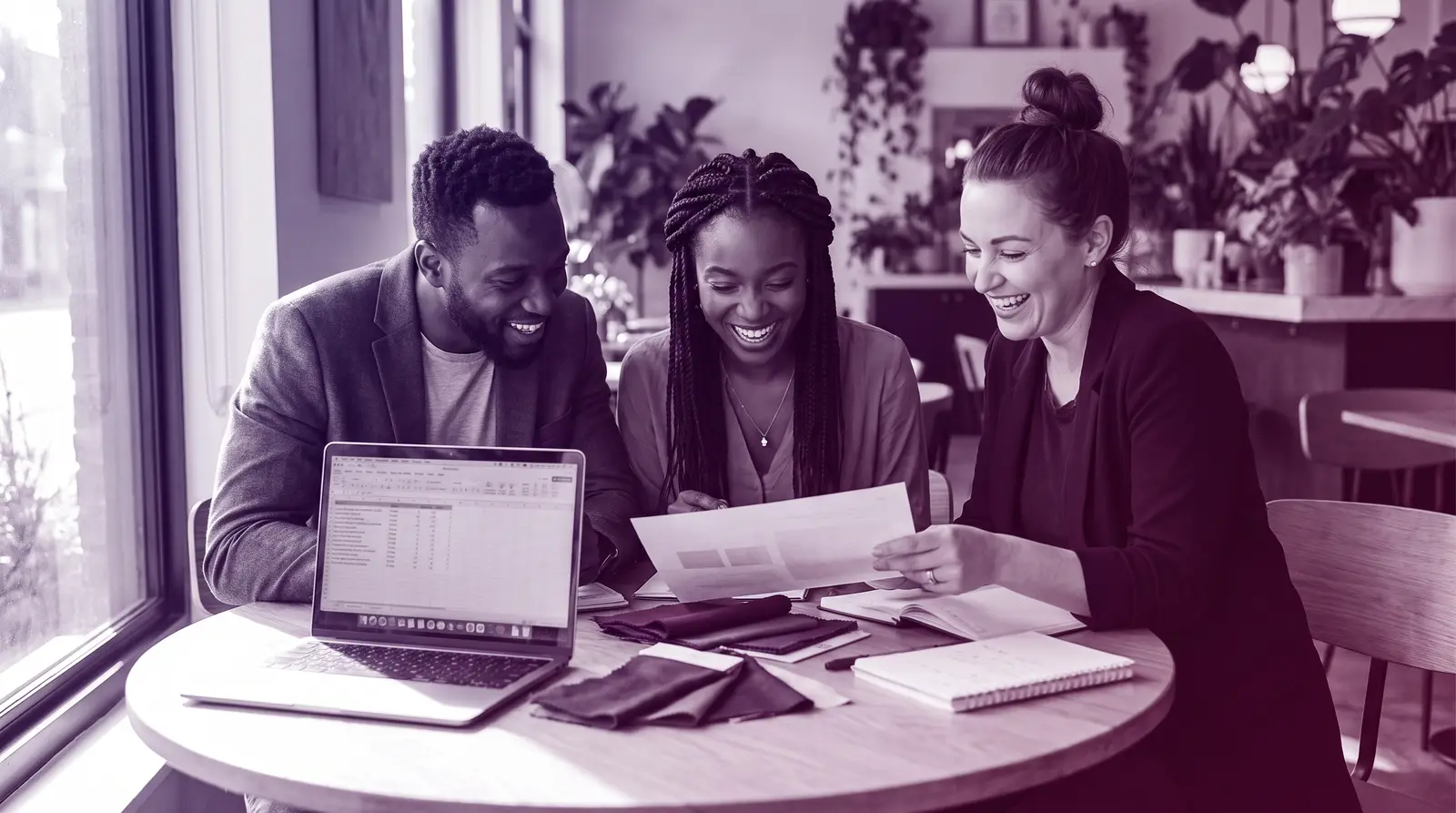 A Black couple reviews wedding plans with their planner at a bright table