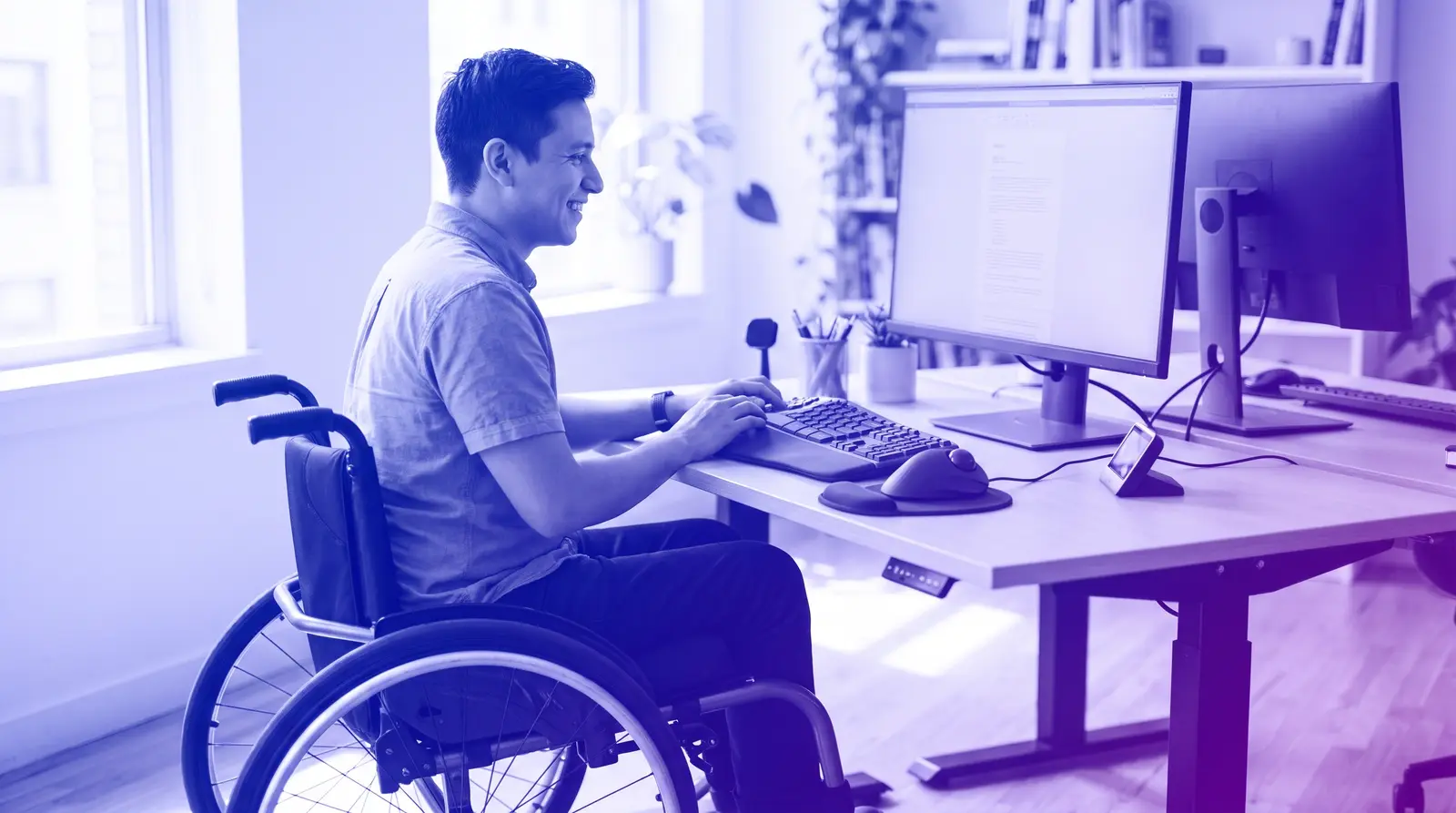 A professional using a wheelchair works at an accessible desk setup