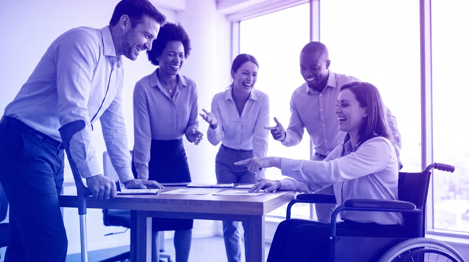 A diverse team including a disabled colleague collaborates around a table