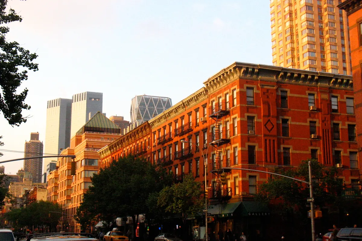 Brick tenement buildings along Ninth Avenue in Hell's Kitchen, with Midtown towers behind