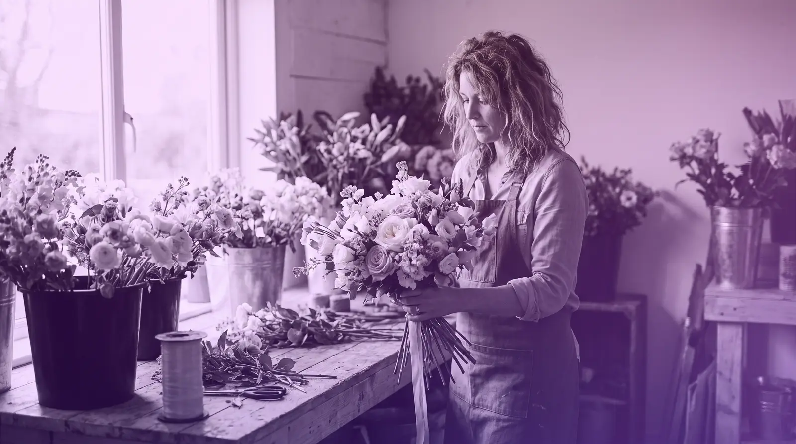 A woman florist arranges a wedding bouquet in her studio