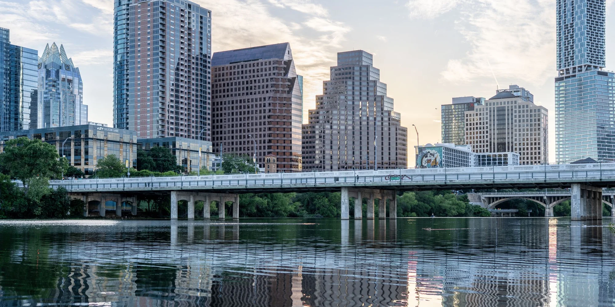 The downtown Austin skyline and the Congress Avenue Bridge reflected in Lady Bird Lake at daybreak