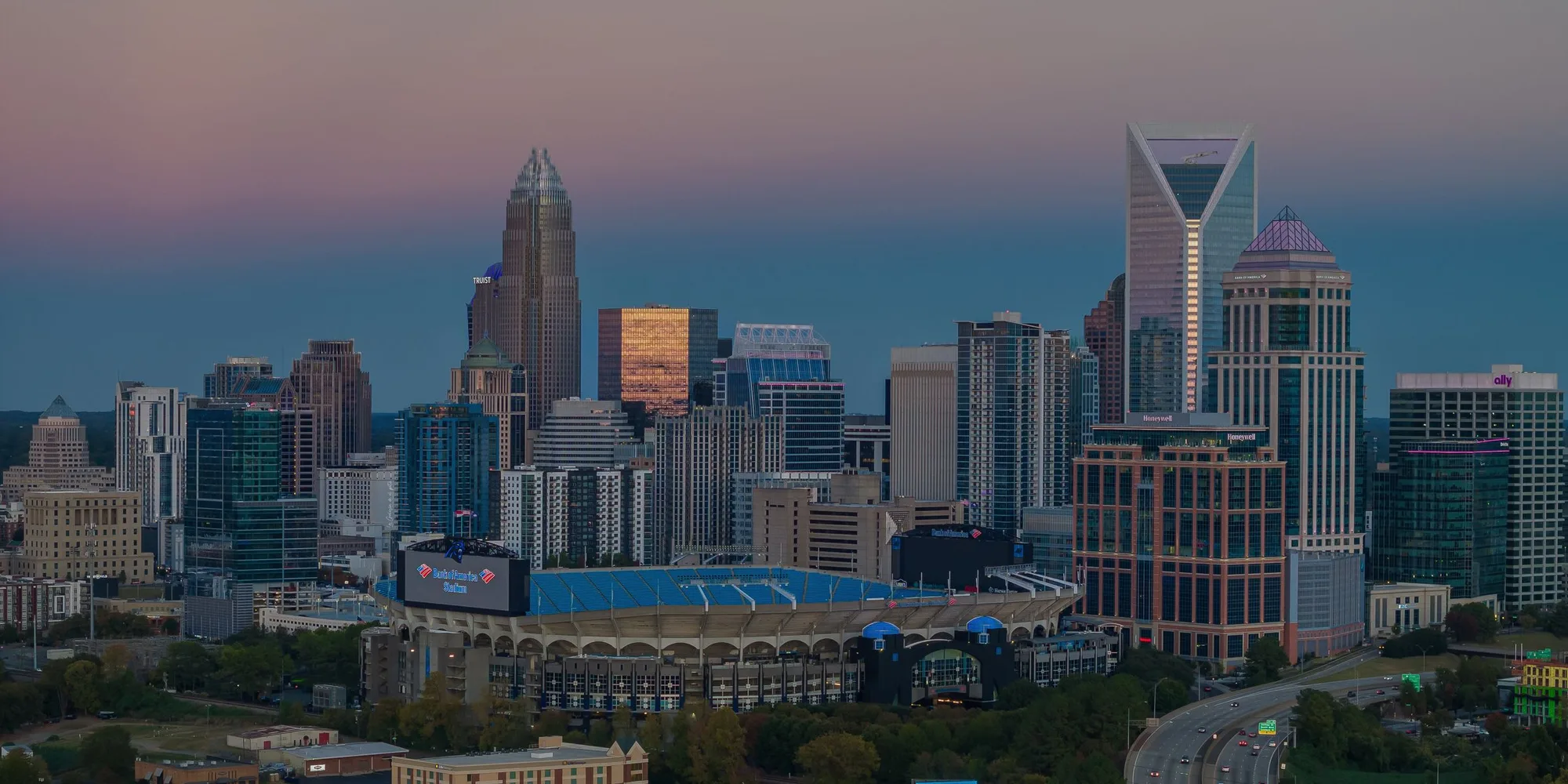 The Charlotte skyline at dusk with Bank of America Stadium in the foreground
