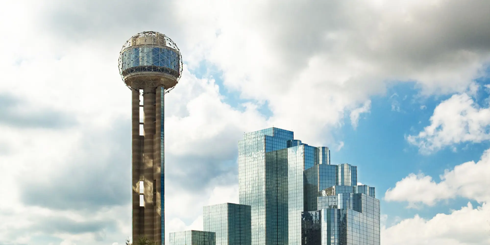Reunion Tower and the downtown Dallas skyline against a cloudy sky