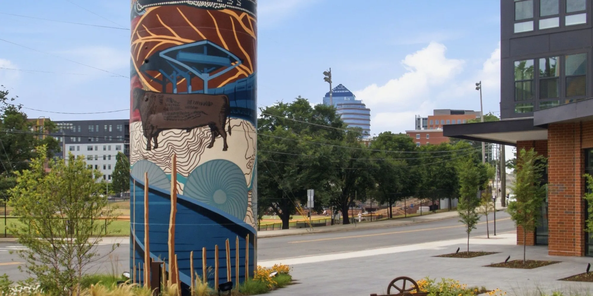 A painted mural on a tower with downtown Durham behind it