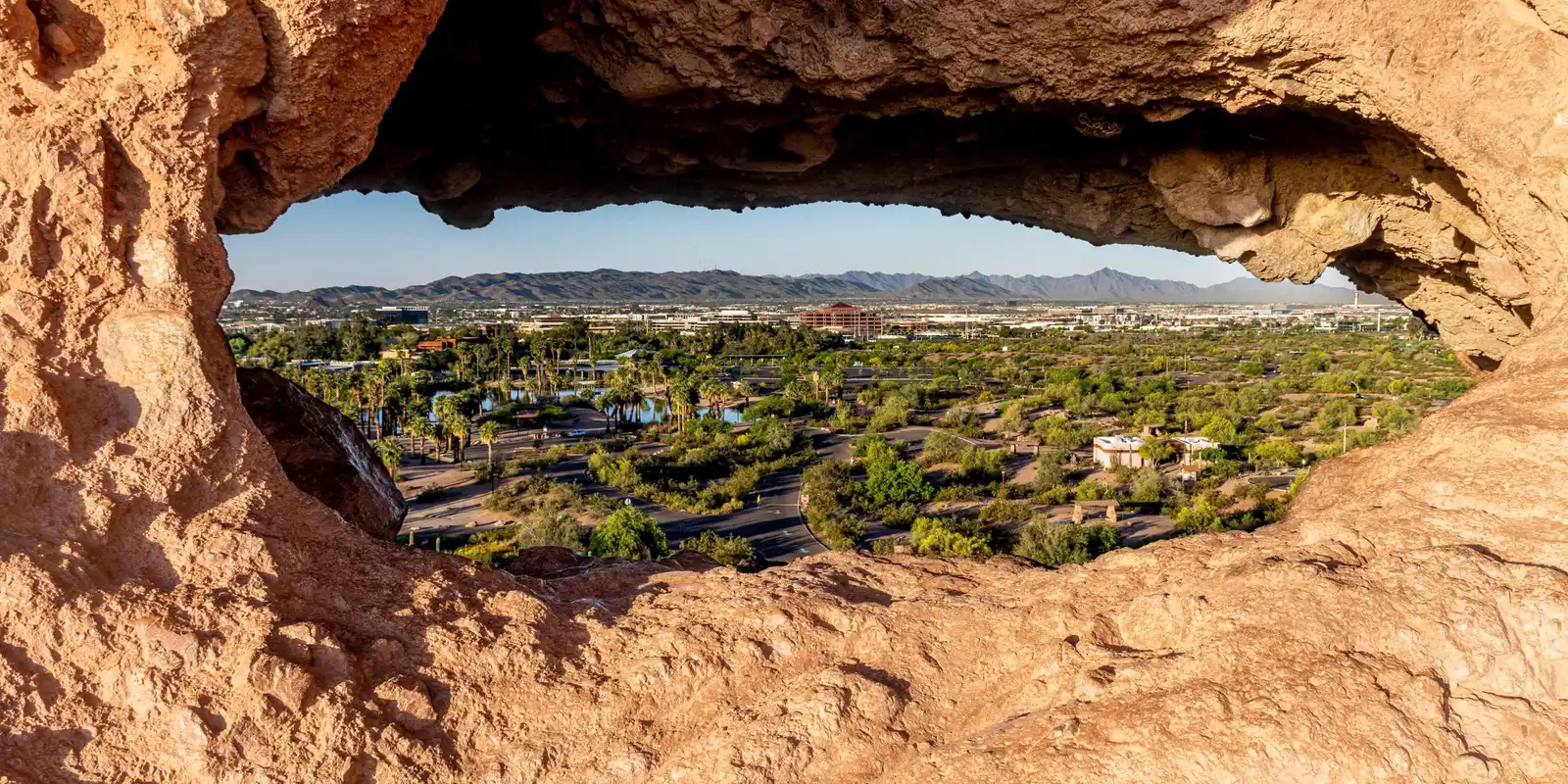 Phoenix and the desert mountains seen through the Hole-in-the-Rock formation at Papago Park