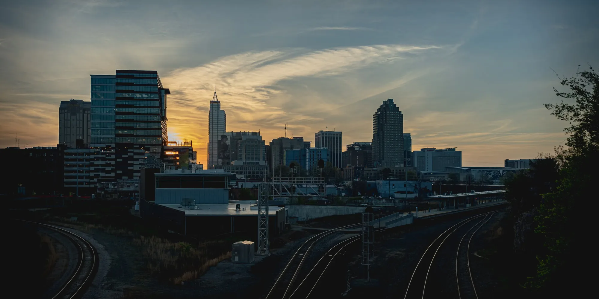 The Raleigh skyline at sunset above the rail lines