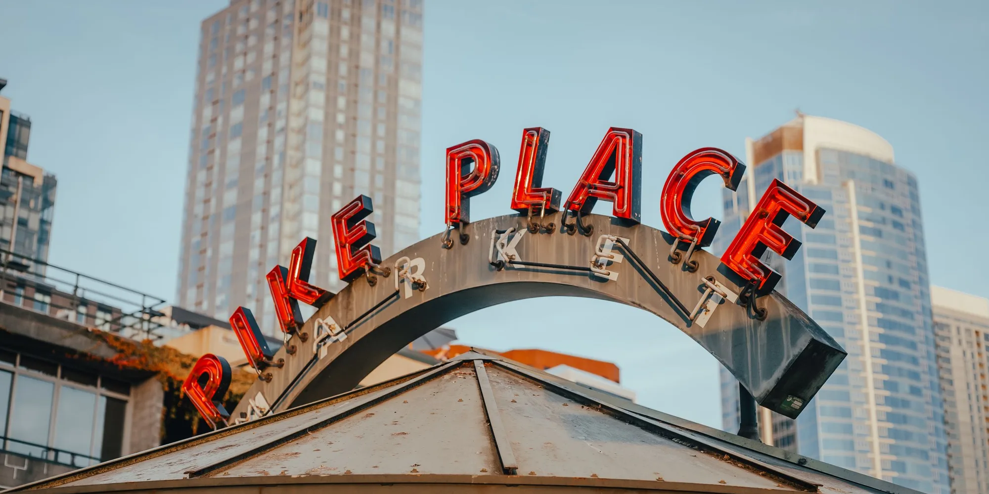 The Pike Place Market sign in Seattle with the downtown towers behind it