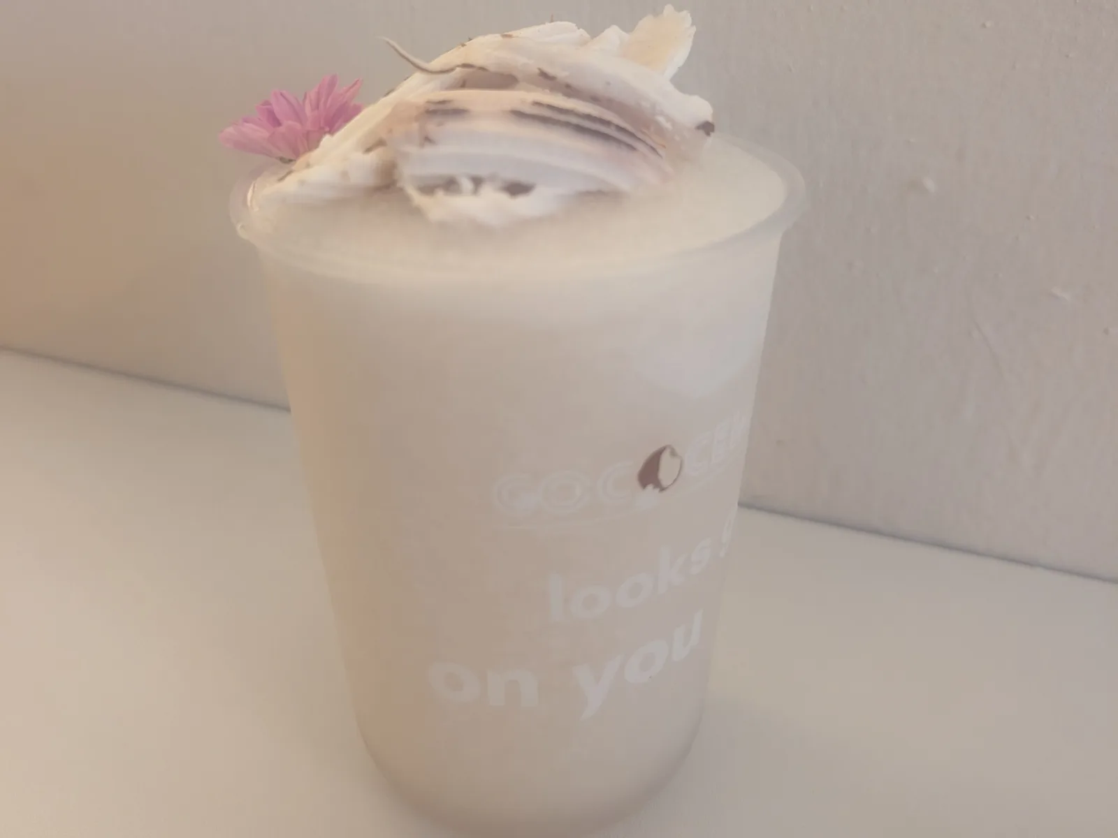 A coconut slushie at Cococello, topped with foam, a coconut chip and a small pink flower